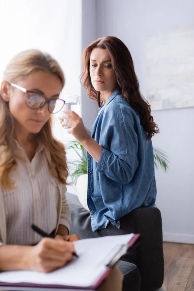 Therapeut Schrijven Medische Geschiedenis Terwijl Patiënt Drinkwater — Stockfoto