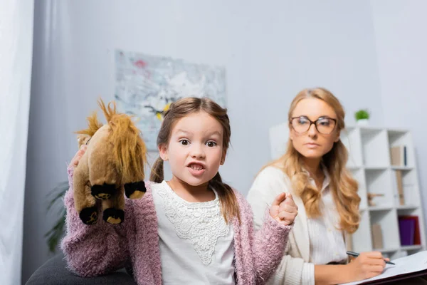 怒った女の子とおもちゃと握りしめ拳訪問心理学者 — ストック写真