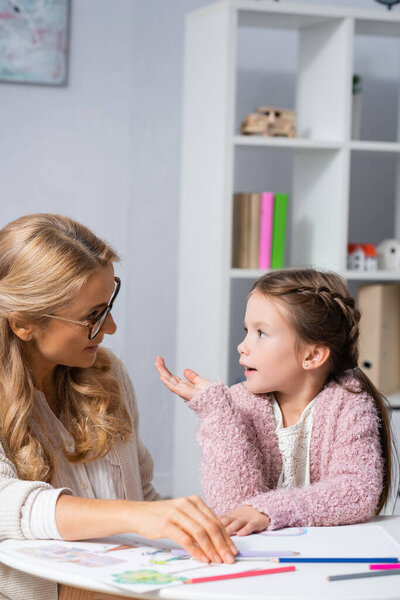 little girl gesturing and looking at psychologist