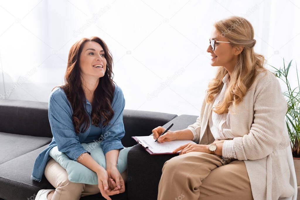 smiling brunette woman having consultation with therapist
