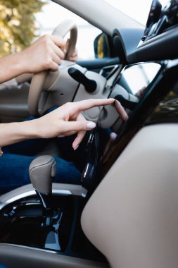 Cropped view of woman using audio system while husband driving auto  clipart