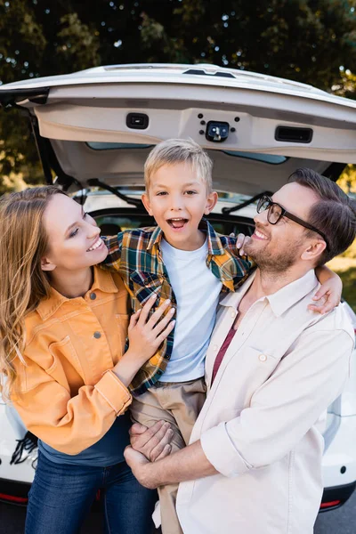 Enfant Heureux Regardant Caméra Tout Embrassant Les Parents Près Voiture — Photo