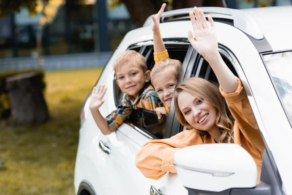 Smiling Woman Waving Camera Children Car Blurred Background — Stock Photo, Image