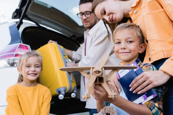 Leende Pojke Med Leksak Stående Nära Familjen Med Pass Resväska — Stockfoto