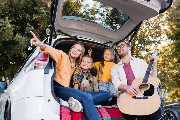 Femme Souriante Pointant Doigt Près Des Enfants Mari Avec Guitare — Photo