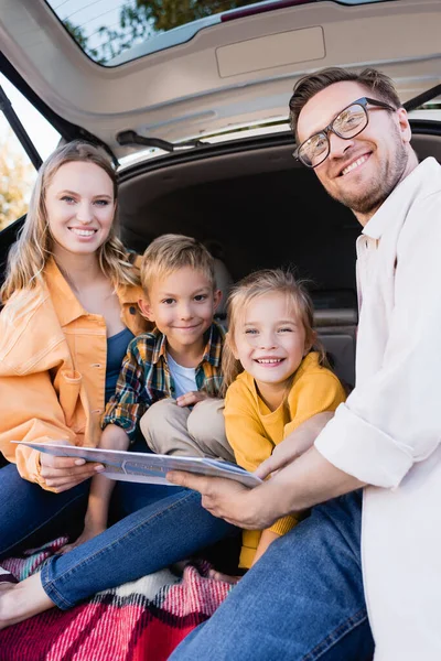 Smiling Family Holding Map While Looking Camera Trunk Car — Stock Photo, Image