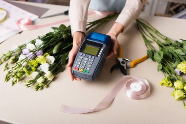 Eustoma çiçeklerinin yanında elinde bulunan çiçekçinin kırpılmış görüntüsü, afiş.