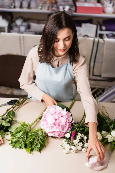 Çiçekçinin Çiçekli Arka Plandaki Çiçeklerin Yakınındaki Masadan Dekoratif Kurdele Aldığı — Stok fotoğraf
