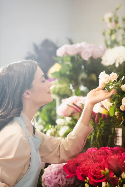 Vista Lateral Florista Morena Sorridente Cuidar Rosas Rack Flores Fundo — Fotografia de Stock