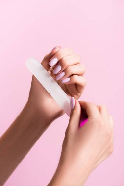 Pembe üzerinde izole edilmiş tırnak törpüsü kullanan kadın görüntüsü