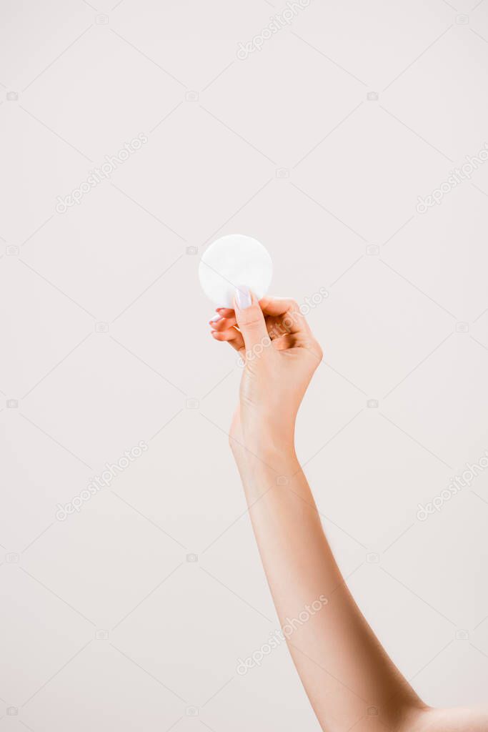 cropped view of woman holding cotton pad isolated on grey