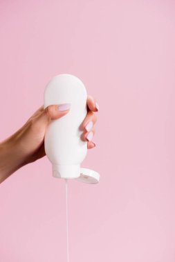 Kırpılmış kadın losyonu pembe üzerine sıkıyor.