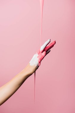 Kırpılmış el manzarası, damlayan boya pembeye izole edilmiş.