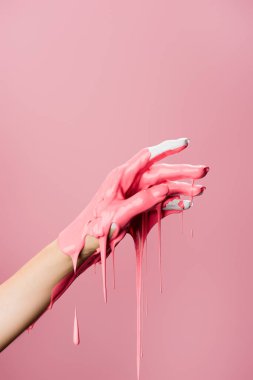 Kırpılmış el manzarası, damlayan boya pembeye izole edilmiş.