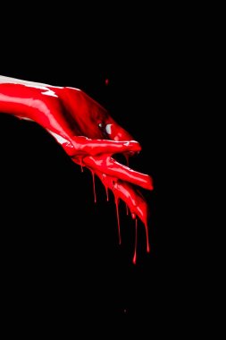 Siyah üzerine kırmızı damlayan boya ile boyanmış elin kısmi görüntüsü