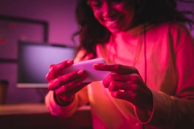 Bulanık arka planda neşeli Afrikalı Amerikalı oyuncunun ellerinde akıllı telefon. 
