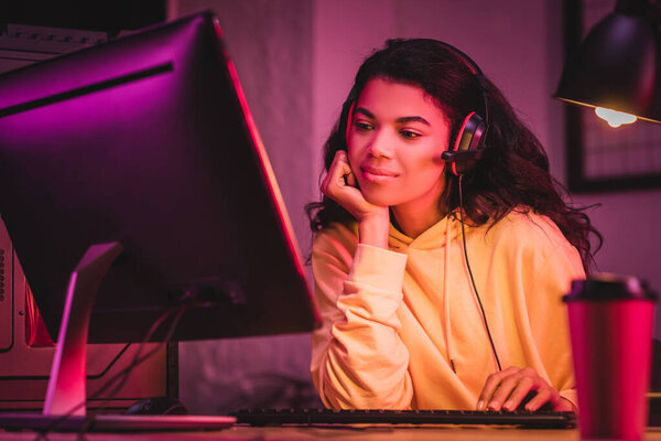 African american woman in headset using computer near coffee to go 