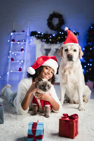 Cheerful African American Girl Cuddling Fluffy Cat While Lying Floor — Stock Photo, Image