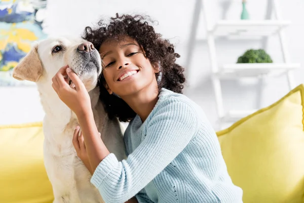 Sonriente Chica Afroamericana Apoyada Retriever Mientras Está Sentada Sofá Amarillo — Foto de Stock