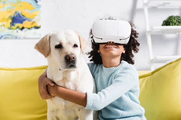 Smiling Curly African American Girl Hugging Retriever While Wearing Headset — Stock Photo, Image