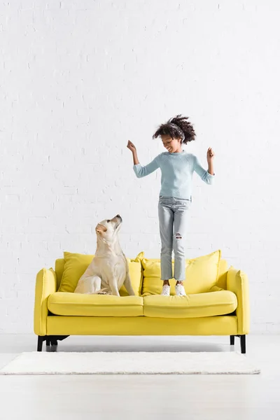 Happy African American Girl Hands Air Standing Sofa While Looking — Stockfoto