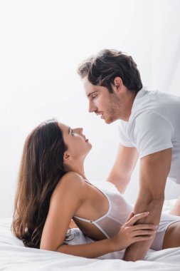 Tutkulu bir adamın vücut kıyafetli baştan çıkarıcı kız arkadaşına bakışının yan görüntüsü. 