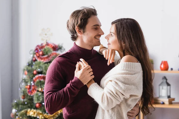 クリスマスツリーの近くに飾られた暖かい気候の幸せなカップルの側の景色を背景にぼやけた — ストック写真