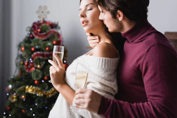 Paar Holding Bril Met Champagne Knuffelen Buurt Van Kerstboom Wazig — Stockfoto