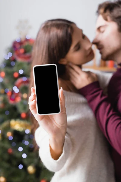 Woman Holding Smartphone Blank Screen Boyfriend Decorated Christmas Tree Blurred — Stock Photo, Image