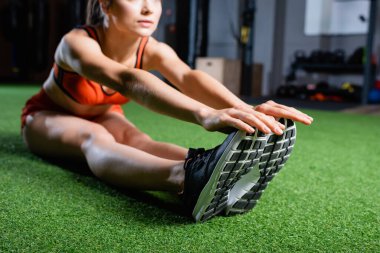 Spor salonundaki spor salonunun önünde otururken spor ayakkabısına dokunan kadın manzarası bulanık arka plan.