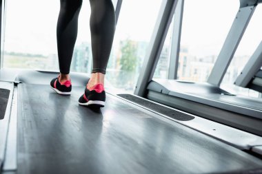 Koşu bandında spor ayakkabısı ve tayt giymiş spor kadın manzarası.