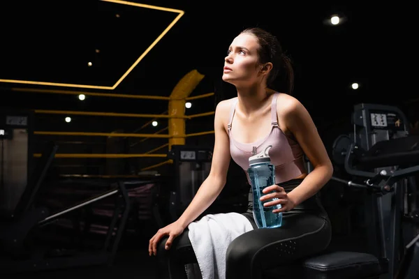 Young Sportswoman Looking Away While Sitting Training Machine Sports Bottle — Stock Photo, Image