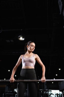 Sporcu kadın üstte ve tozluklarla spor salonunda spor yapıyor.