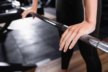 Bulanık arkaplanda güç rafına dokunan sporcu kadının kırpılmış görüntüsü
