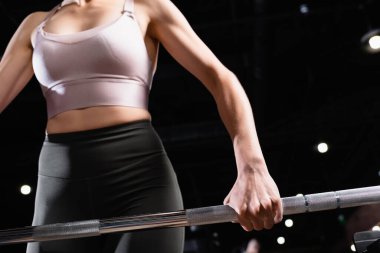 Sporcu kadının spor merkezindeki güç raflarını kaldırma görüntüsü.