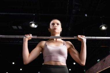 Genç sporcu kadın spor salonunda güç askısı ile çalışıyor.