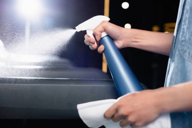 partial view of charwoman spraying detergent on treadmill in sports center clipart