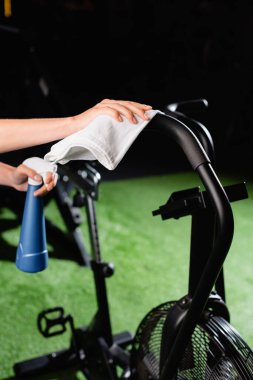cropped view of charwoman wiping exercising machine in sports center clipart