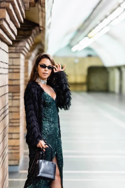 Glamour Woman Black Lurex Dress Touching Sunglasses While Standing Underground — Stock Photo, Image