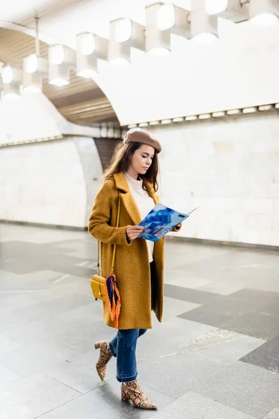 Young Woman Stylish Autumn Outfit Reading Magazine While Walking Underground — Foto de Stock