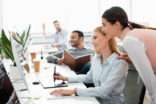 Lächelnde Geschäftsfrau Mit Computer Und Grafik Tablet Neben Multiethnischen Kollegen — Stockfoto