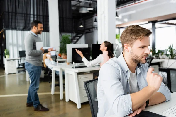 Empresario Sosteniendo Pluma Cerca Del Teclado Computadora Mientras Colegas Multiétnicos — Foto de Stock