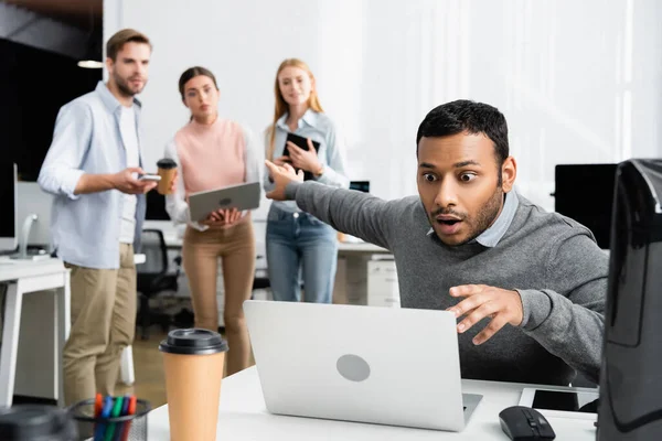 Excited Indian Businessman Looking Laptop Colleagues Blurred Background Office — Stock Photo, Image