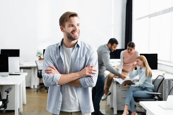 Smiling Businessman Crossed Arms Standing Multicultural Colleagues Blurred Background Office — Stock Photo, Image