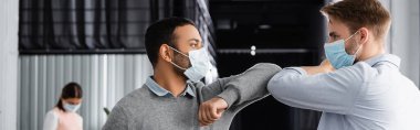 Tıp maskeli çok ırklı işadamları, dirsekleriyle ve pankartıyla beşlik çakıyor. 