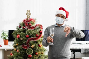 Tıbbi maskeli Hintli işadamı elinde şampanyayla ve ofisteki noel ağacının yanında hoş olmayan hareketler sergiliyor. 