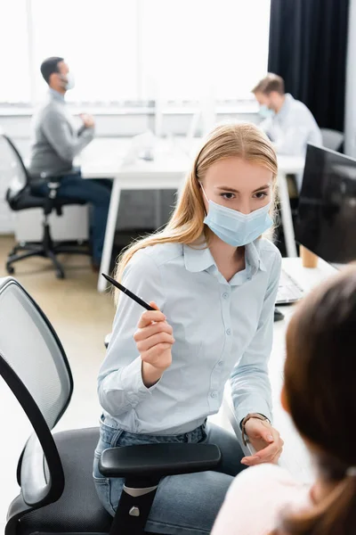 Businesswoman Medical Mask Holding Pen Colleague Blurred Foreground — Stock Photo, Image