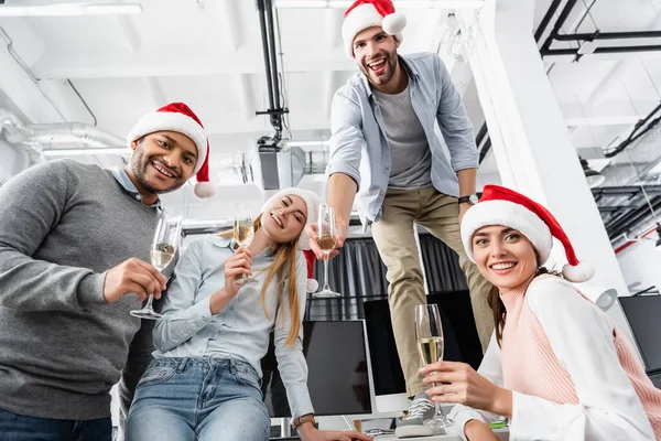 Lächelnde Multikulturelle Geschäftsleute Mit Weihnachtsmannhüten Und Champagnergläsern Büro — Stockfoto