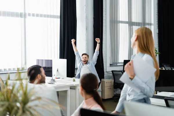 Cheerful Businessman Showing Yeah Gesture Computer Multiethnic Colleagues Blurred Foreground — Stock Photo, Image