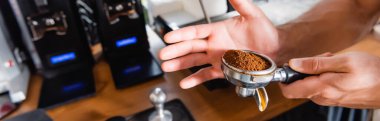partial view of barista holding portafilter with roasted ground coffee, banner clipart